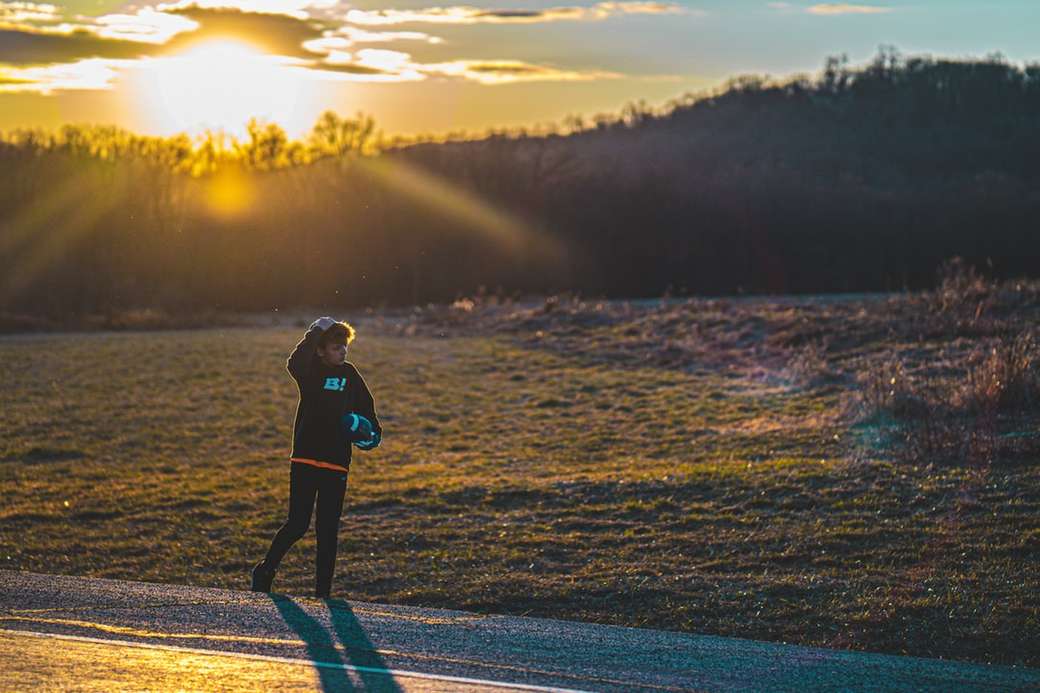 kobieta w czarnej kurtce spaceru na drodze podczas zachodu słońca puzzle online
