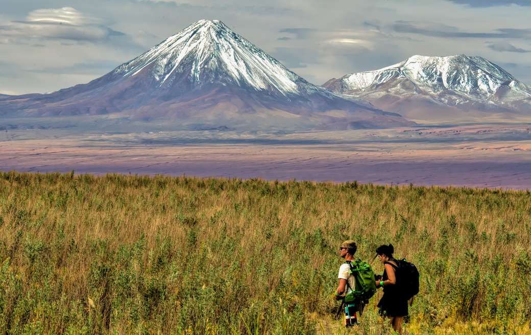 mężczyzna i kobieta siedzi na polu trawy w pobliżu góry w ciągu dnia puzzle online