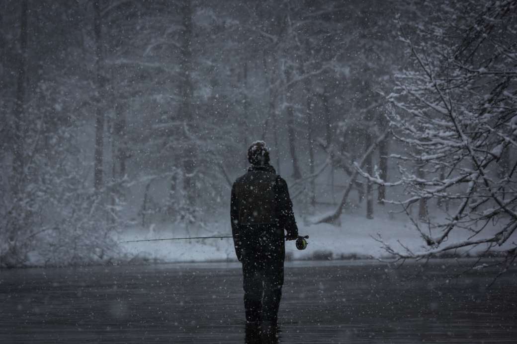 fotografia w skali szarości przedstawiająca człowieka łowiącego ryby podczas opadów śniegu puzzle online