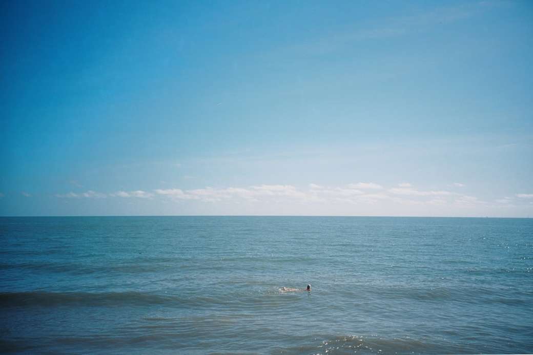 osoba surfuje po morzu pod błękitne niebo w ciągu dnia puzzle online