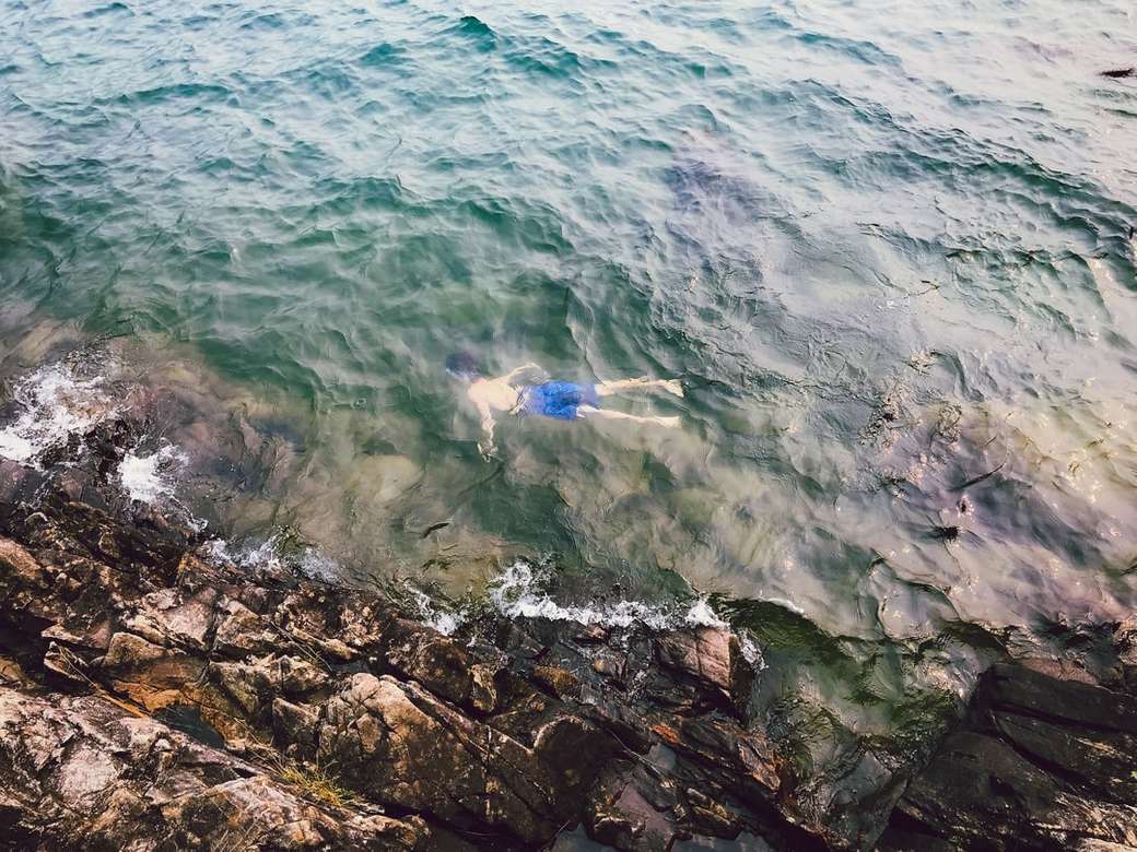 mężczyzna w niebieskim krótkie pływanie na brzegu morza w ciągu dnia puzzle online