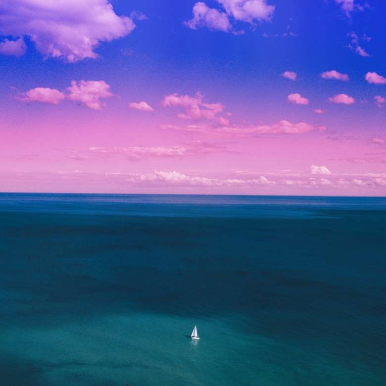 żaglówka na niebieskim oceanie pod fioletowym i niebieskim niebem puzzle online