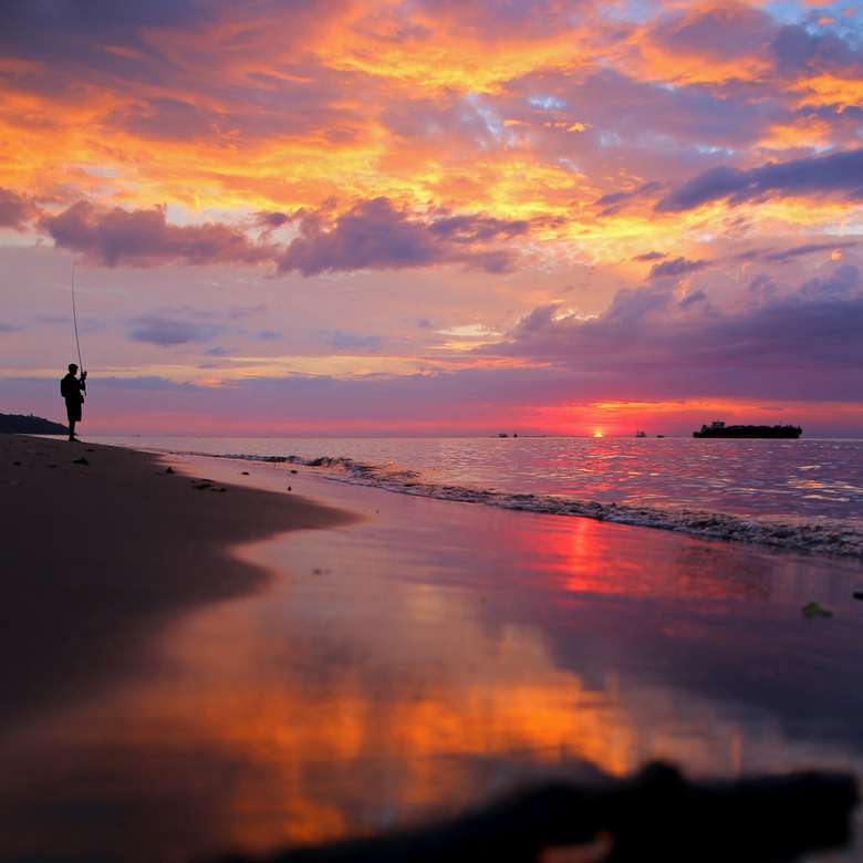 człowiek stojący na brzegu morza podczas złotej godziny puzzle online