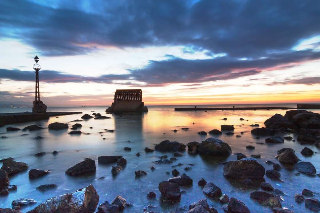 brązowe skały na brzegu morza podczas zachodu słońca puzzle online