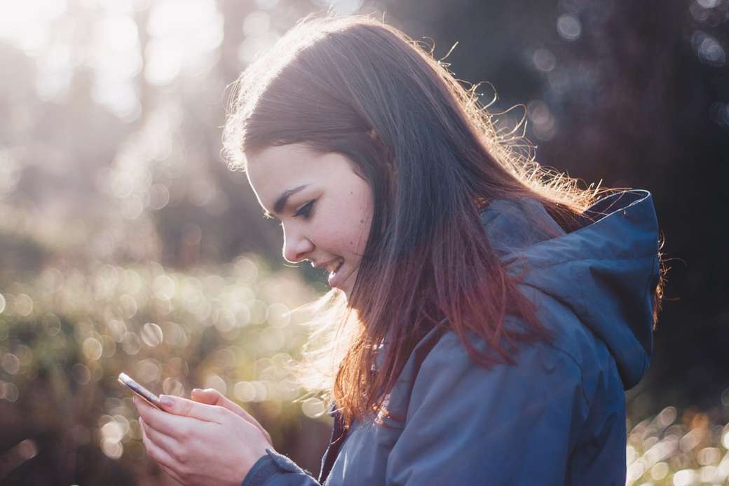 kobieta trzyma telefon z uśmiechem puzzle online