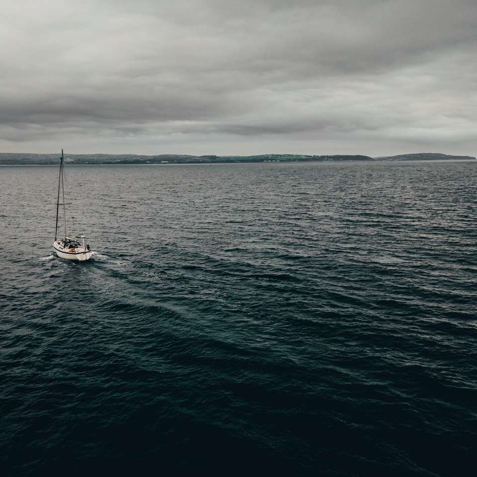 biała łódź na morzu pod zachmurzonym niebem w ciągu dnia puzzle online