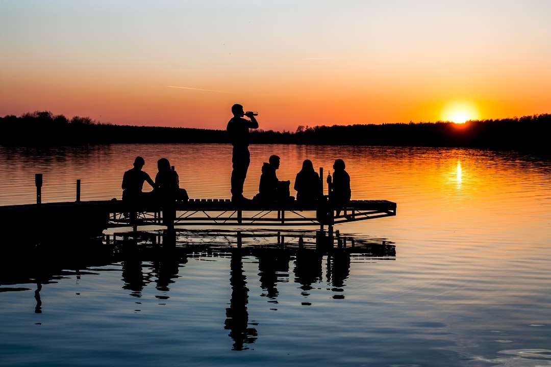 grupa ludzi na drewnianym pomoście podczas zachodu słońca puzzle online