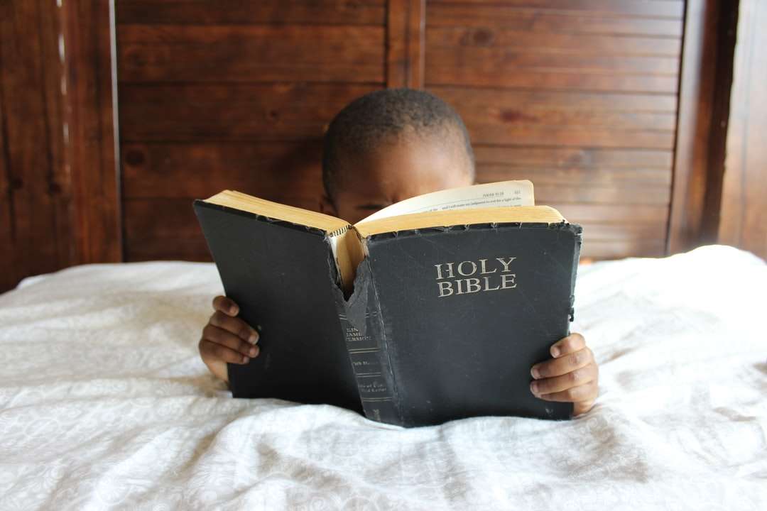 chłopiec czyta Pismo Święte leżąc na łóżku puzzle online