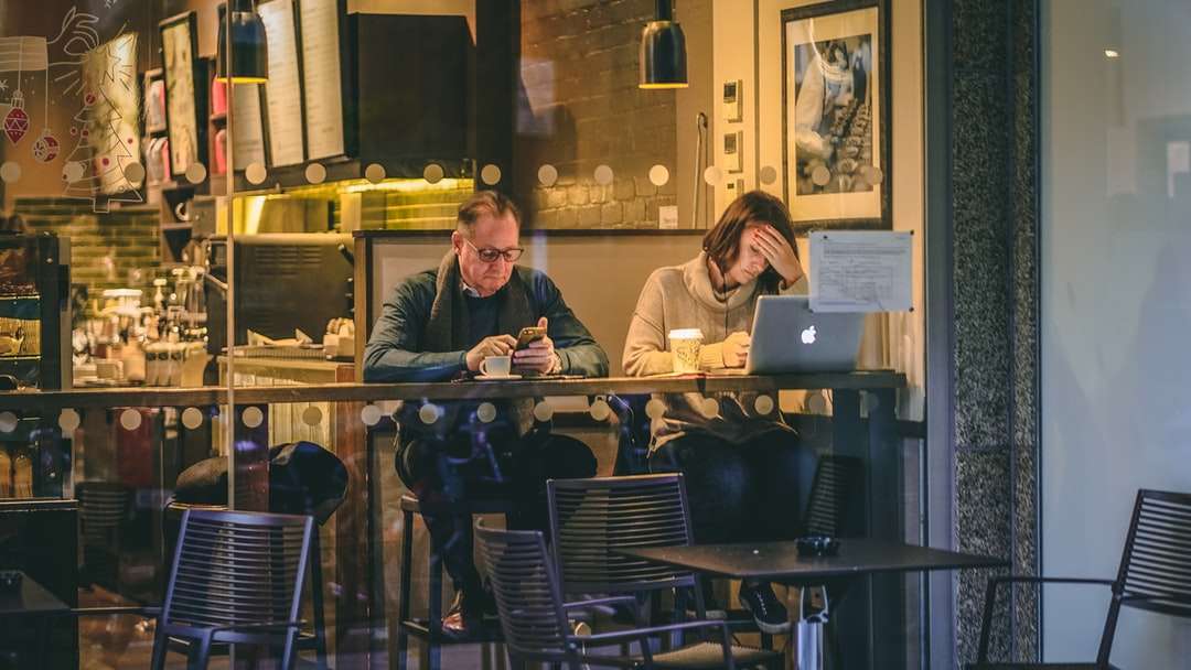 mężczyzna trzyma smartfon siedzący obok kobiety z przodu puzzle online