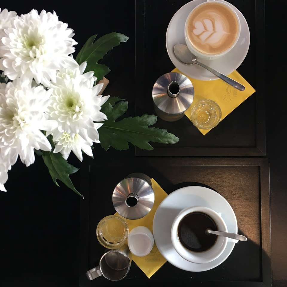 filiżanka kawy obok białych kwiatów puzzle online