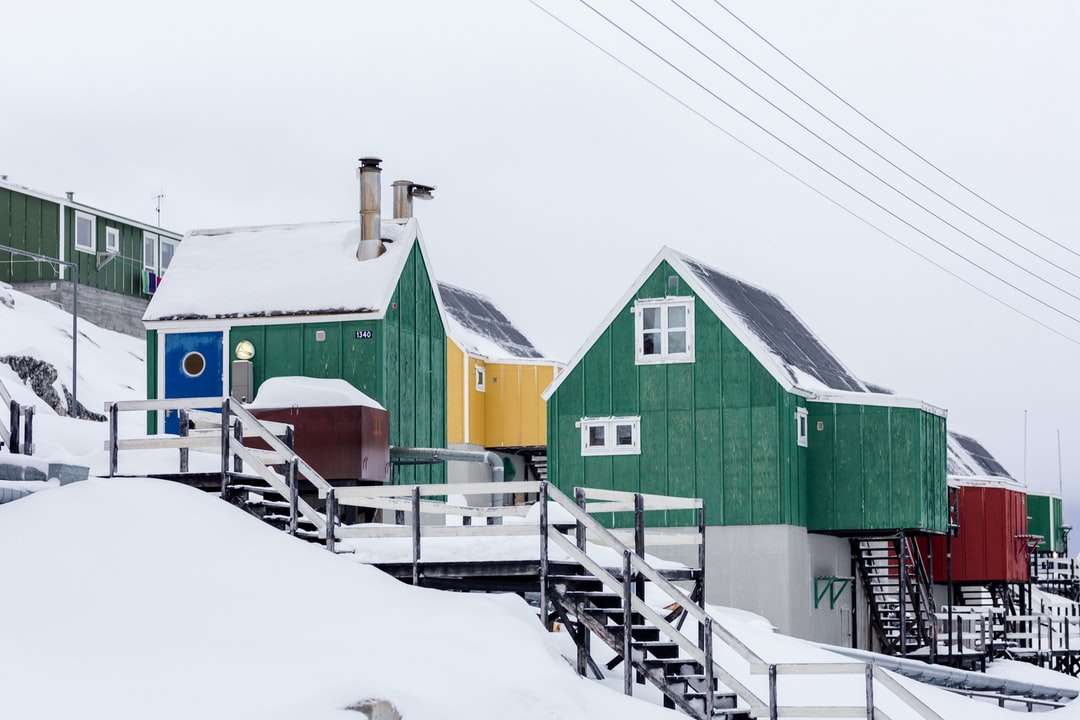 zielone drewniane domy na ośnieżonym stoku pod białym niebem puzzle online