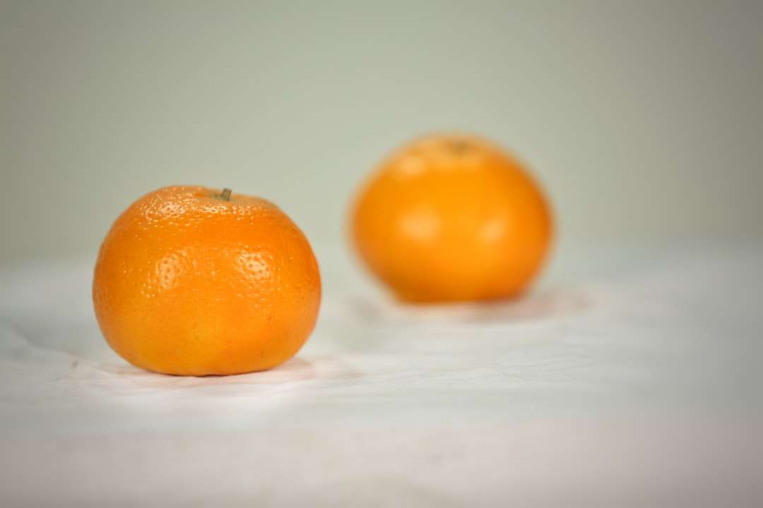 2 pomarańczowe owoce na białej tkaninie puzzle online