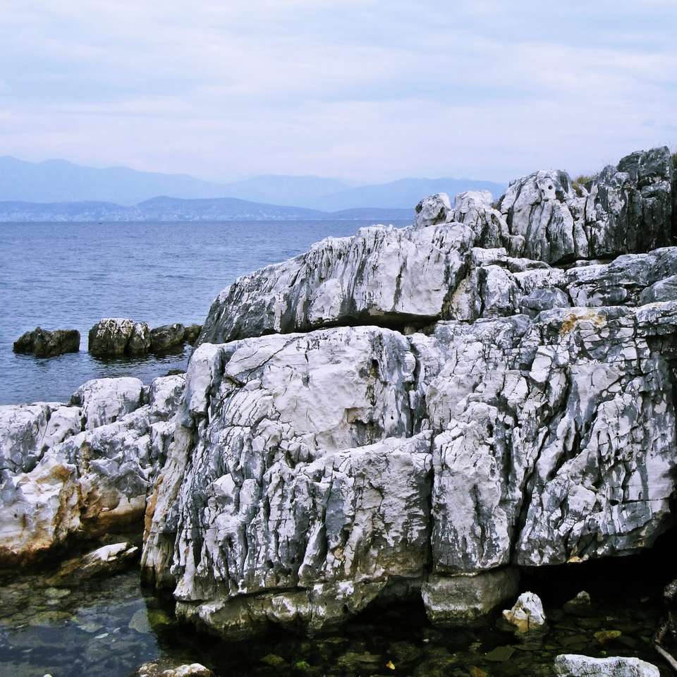 szara formacja skalna w pobliżu zbiornika wodnego w ciągu dnia puzzle online