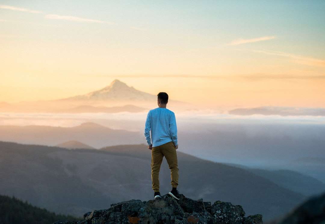 człowiek stojący na szczycie góry puzzle online