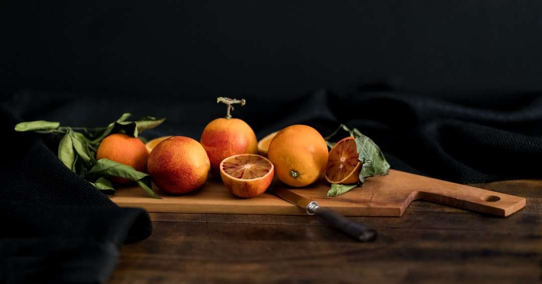 pomarańczowe owoce na brązowej drewnianej desce do krojenia z nożem puzzle online