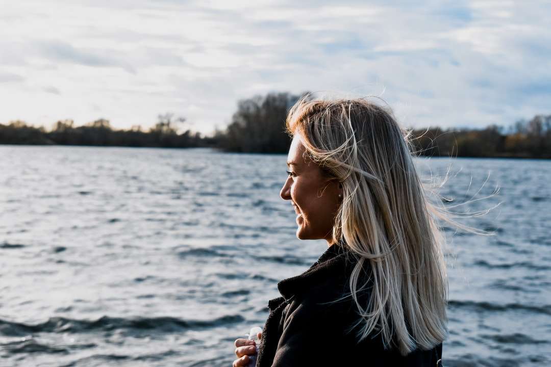 kobieta w czarnej kurtce stojącej w pobliżu zbiornika wodnego puzzle online