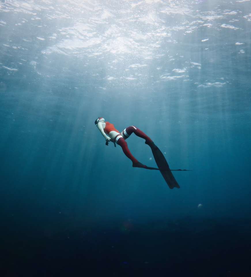 kobieta w białym i czarnym bikini pływanie w morzu puzzle online