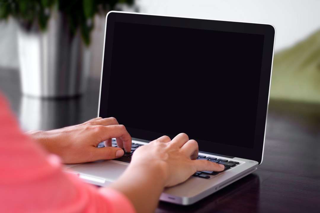 osoba ubrana w różową koszulę wpisując na szarego laptopa puzzle online