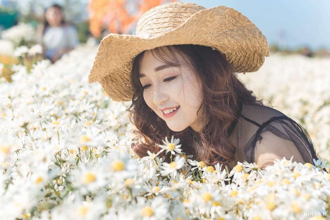 kobieta w brązowym kapeluszu słonecznym stojącym obok białych kwiatów puzzle online