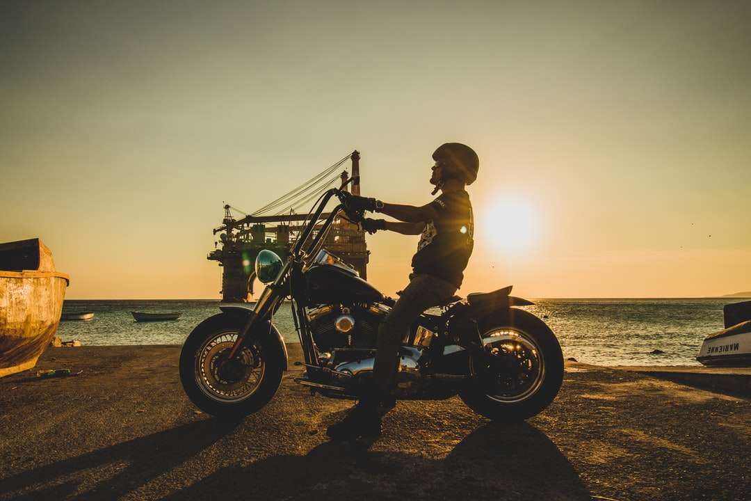 mężczyzna na motocyklu na plaży podczas zachodu słońca puzzle online