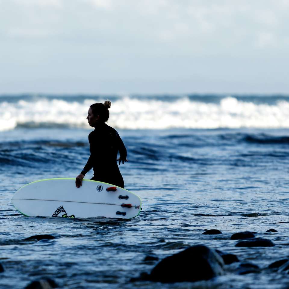kobieta trzyma białą deskę surfingową na zbiorniku wodnym puzzle