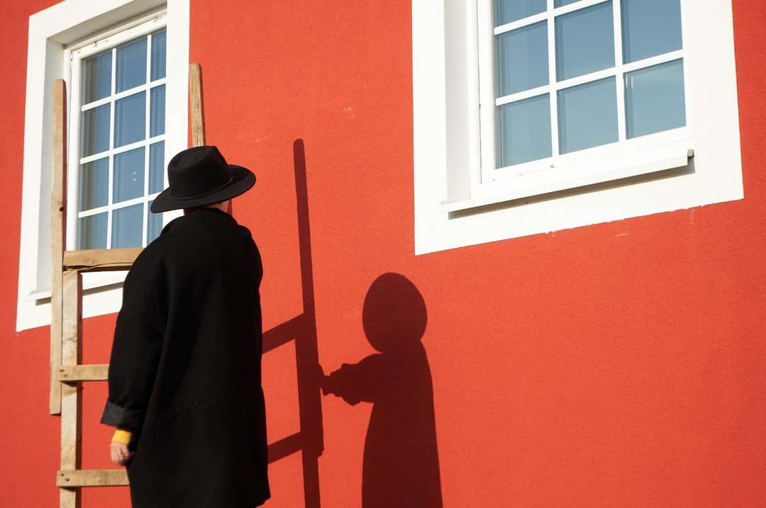 mężczyzna w czarnym kapeluszu stojący przed oknem puzzle online