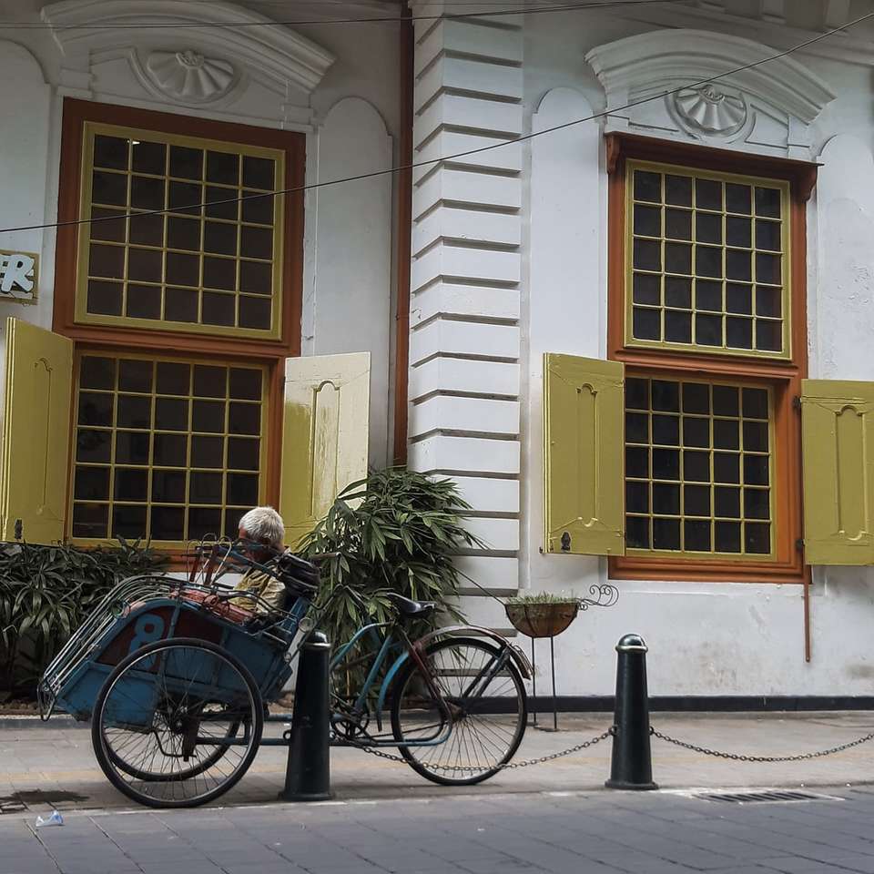 niebieski rower miejski zaparkowany obok biało-brązowego betonowego budynku puzzle online