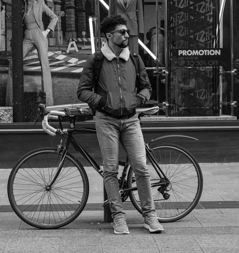 człowiek oparty na pachołku w pobliżu roweru puzzle online