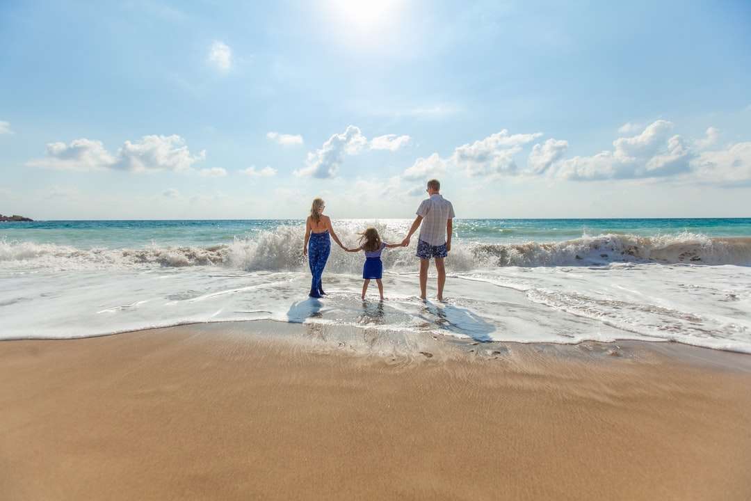 mężczyzna, kobieta i dziecko, trzymając się za ręce nad brzegiem morza puzzle online