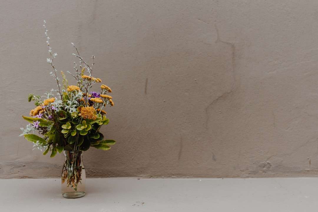 żółte i białe kwiaty w przezroczystym szklanym wazonie puzzle online