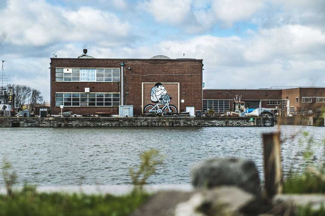 brązowy betonowy budynek w pobliżu zbiornika wodnego w ciągu dnia puzzle online