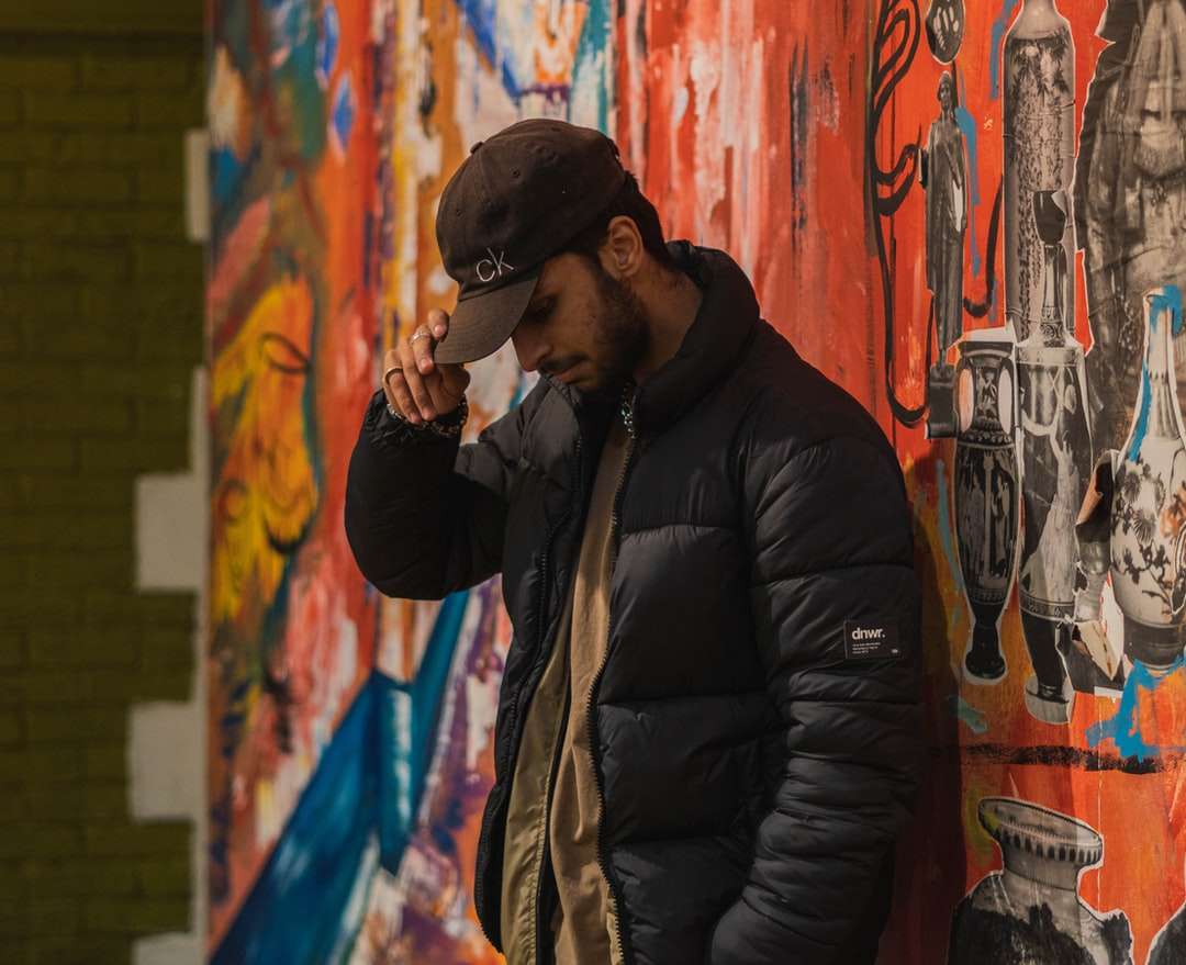 mężczyzna w czarnej kurtce stojący obok ściany graffiti puzzle online
