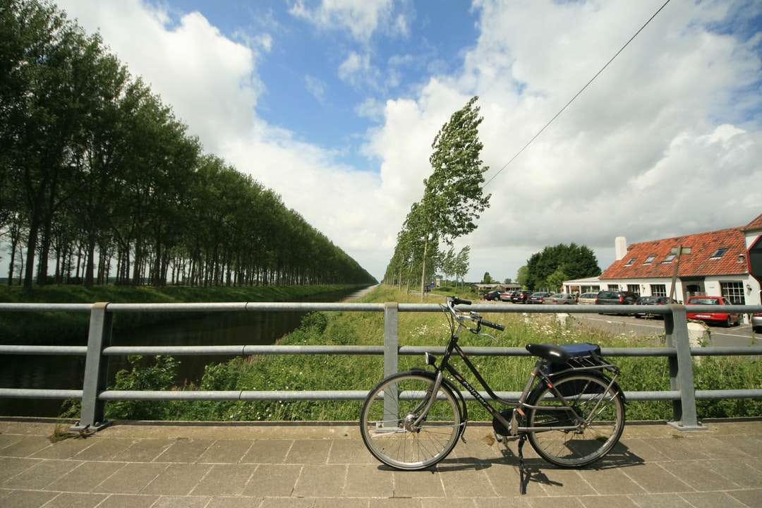 czarny rower zaparkowany obok zielonego metalowego ogrodzenia puzzle online