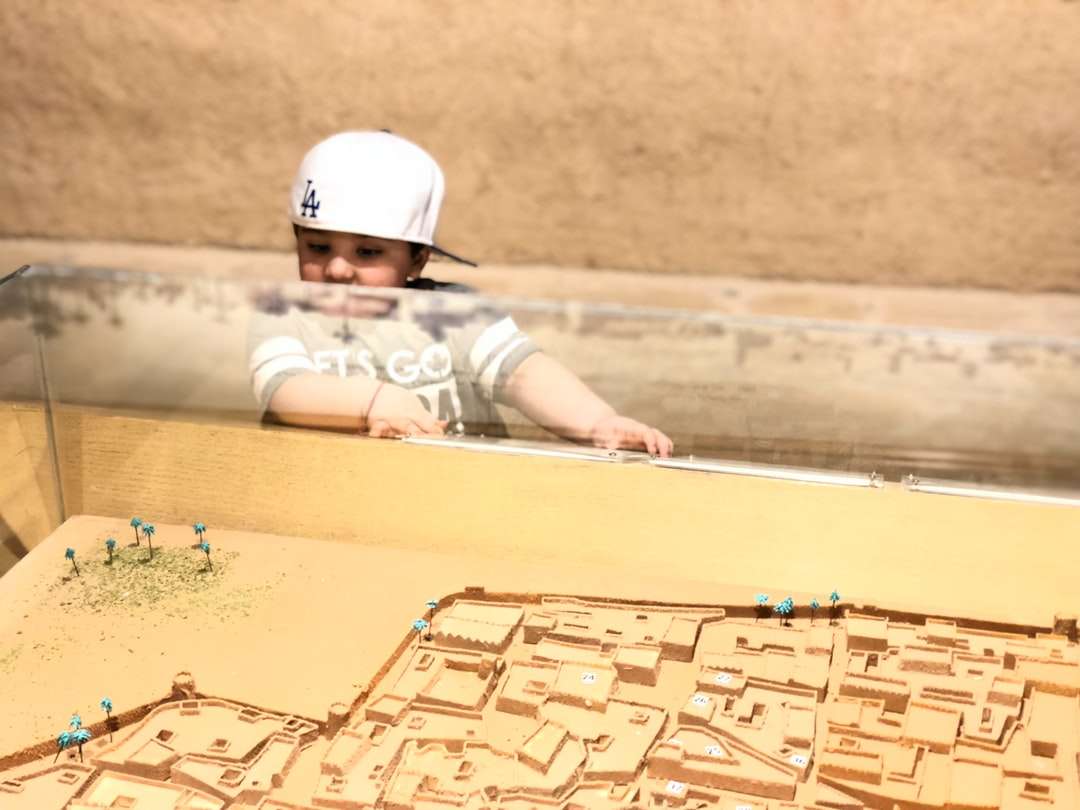 dziecko w białym kasku leżące na brązowym piasku w ciągu dnia puzzle online