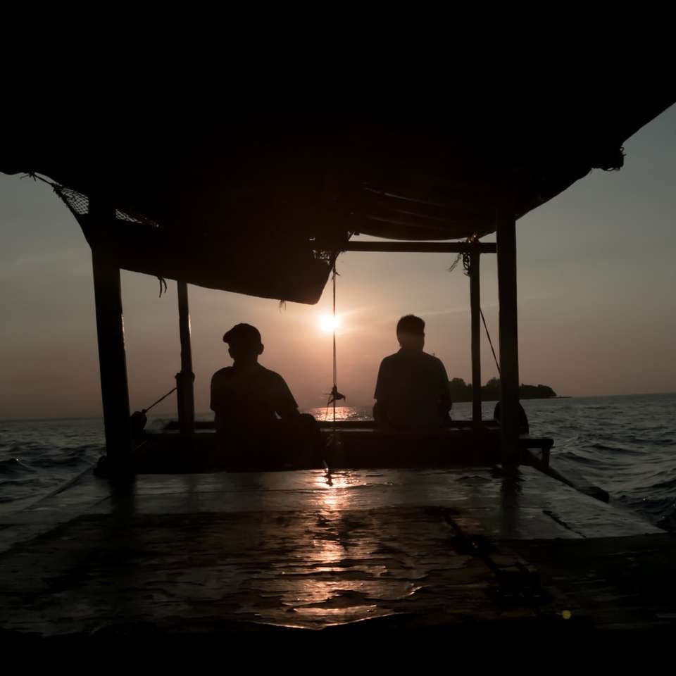 dwie sylwetki osoby siedzącej w pobliżu oceanu w nocy puzzle online