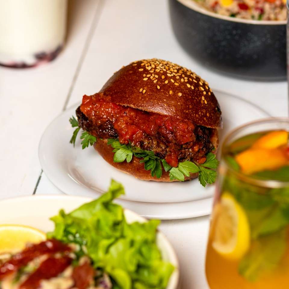 burger na białym talerzu ceramicznym obok przezroczystej szklanki puzzle online