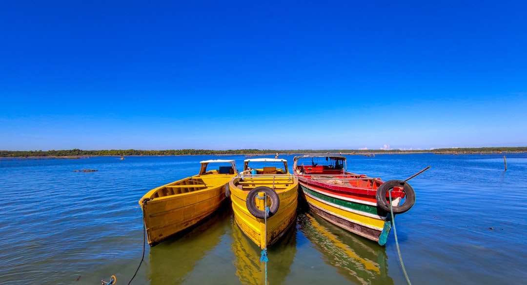 czerwony i żółty łódź na wodzie pod błękitnym niebem w ciągu dnia puzzle online