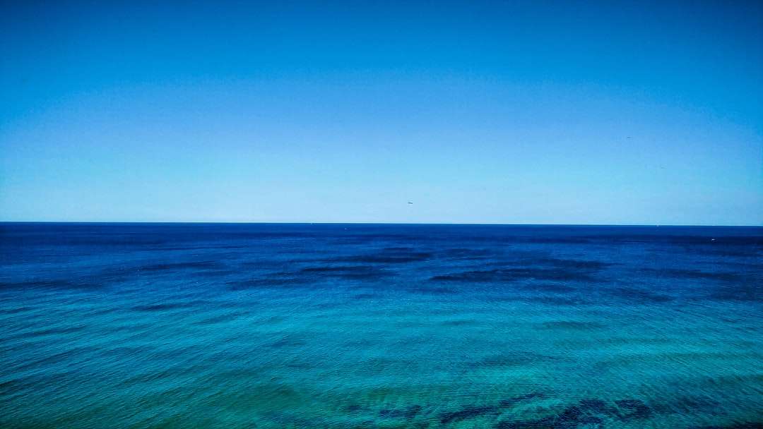 błękitna woda oceaniczna pod błękitnym niebem w ciągu dnia puzzle online