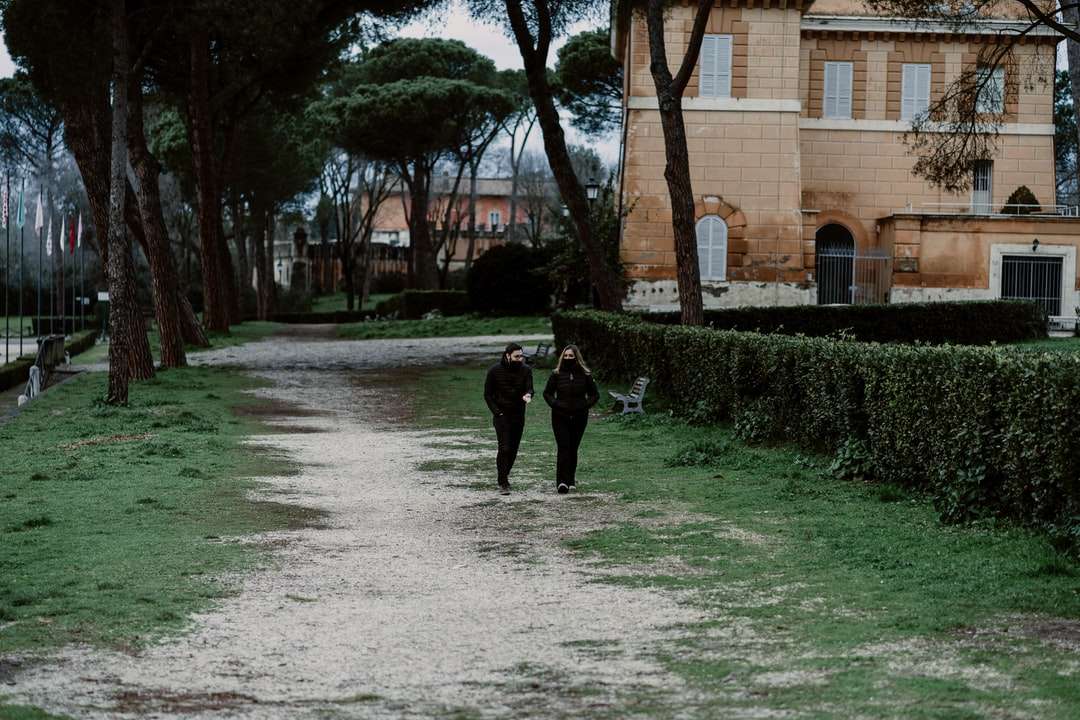 osoba w czarnej kurtce idąca po szarej betonowej ścieżce puzzle online