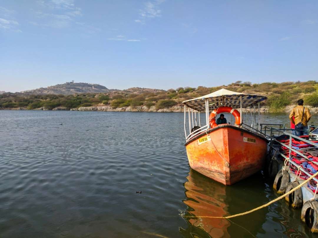 brązowo-biała łódź na wodzie w ciągu dnia puzzle online