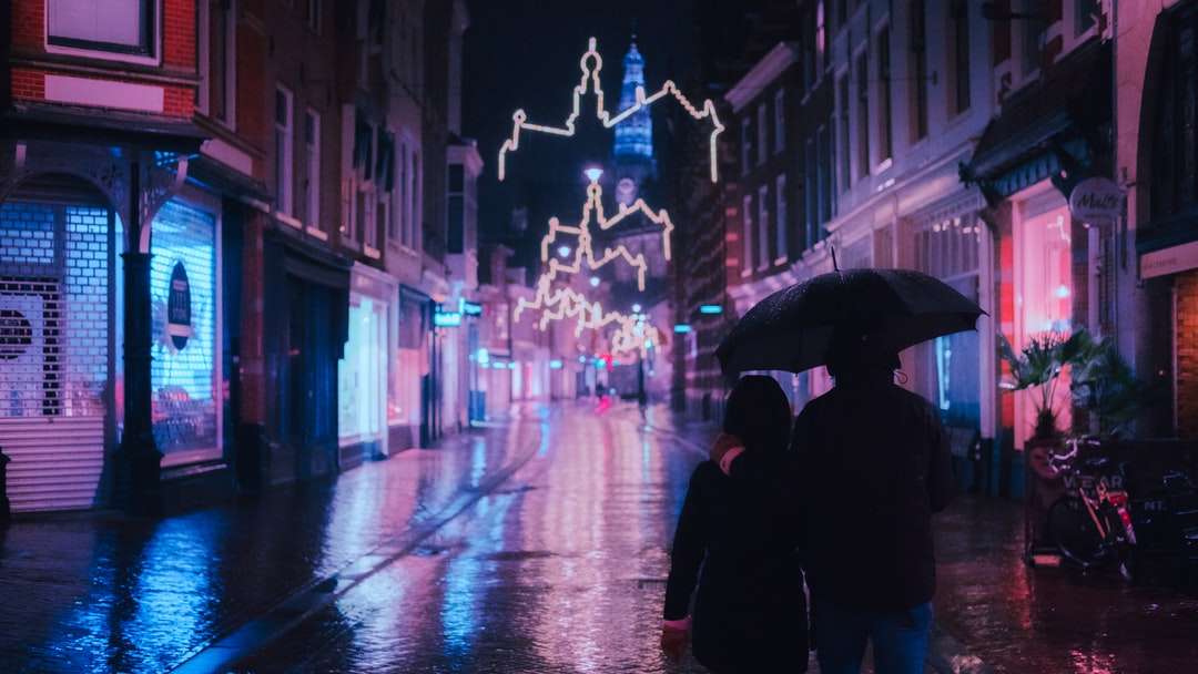 osoba w czarnym płaszczu trzymająca parasolkę na ulicy puzzle online