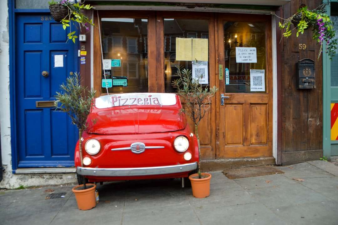 czerwony volkswagen t-2 van zaparkowany obok brązowego drewnianego budynku puzzle online