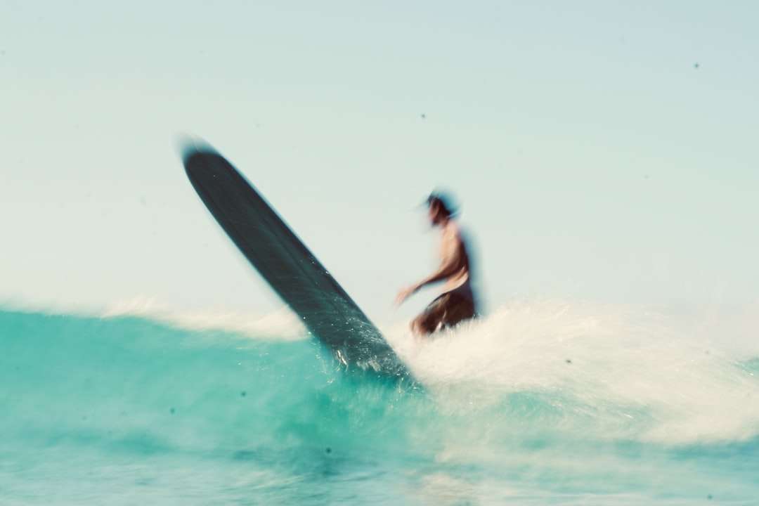 mężczyzna w czarnym kombinezonie surfing na falach morskich w ciągu dnia puzzle online