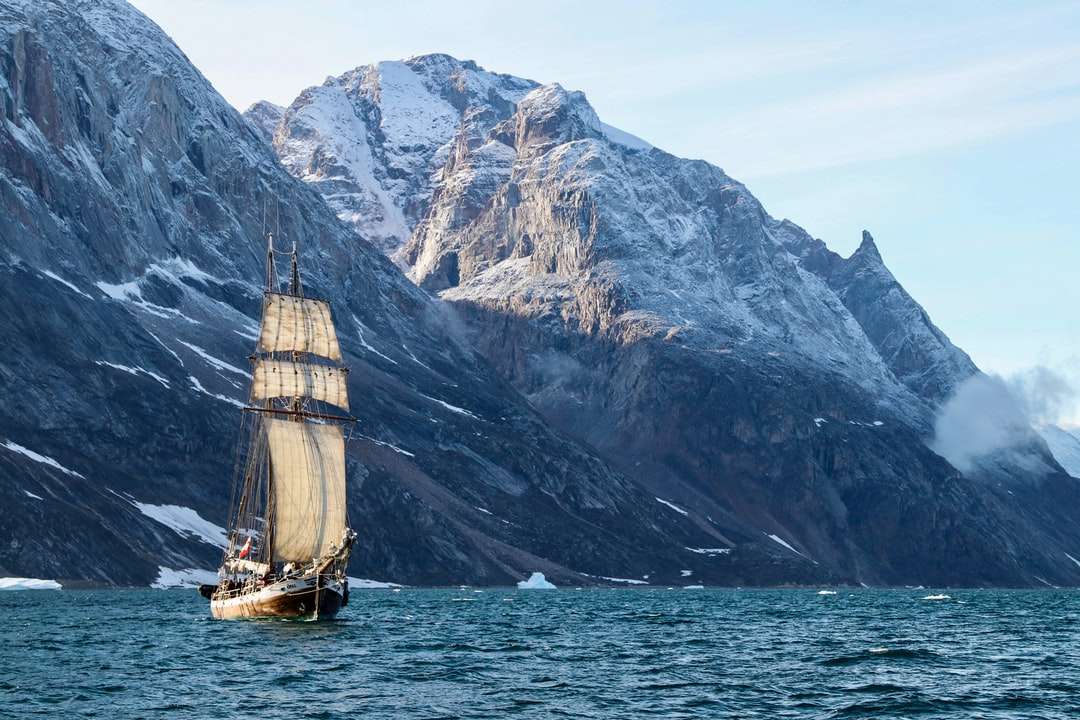 brązowy i biały łódź na morzu w pobliżu góry w ciągu dnia puzzle online