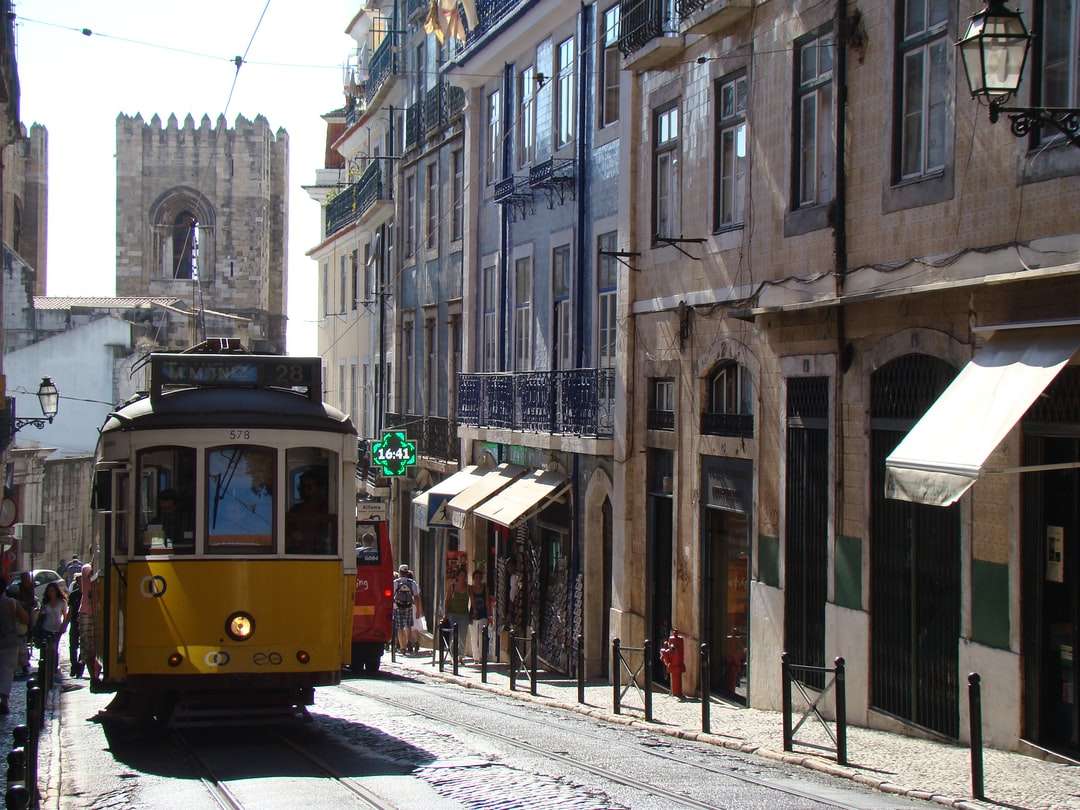 żółty i czerwony tramwaj na drodze w pobliżu budynku w ciągu dnia puzzle online