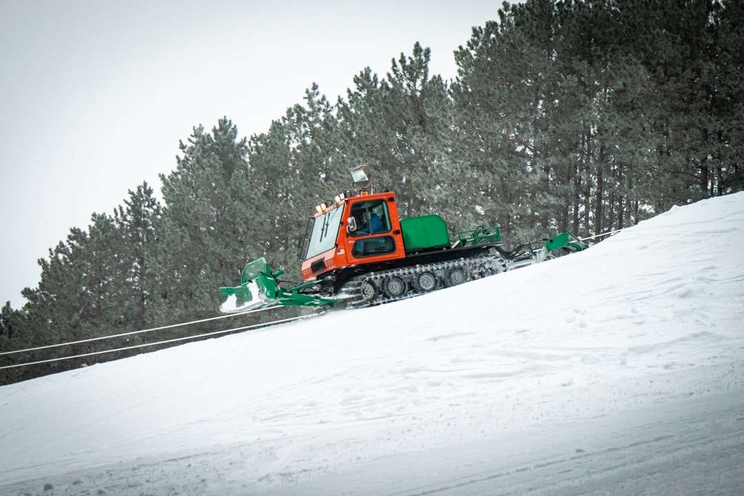 zielony i pomarańczowy traktor na ziemi pokrytej śniegiem puzzle online
