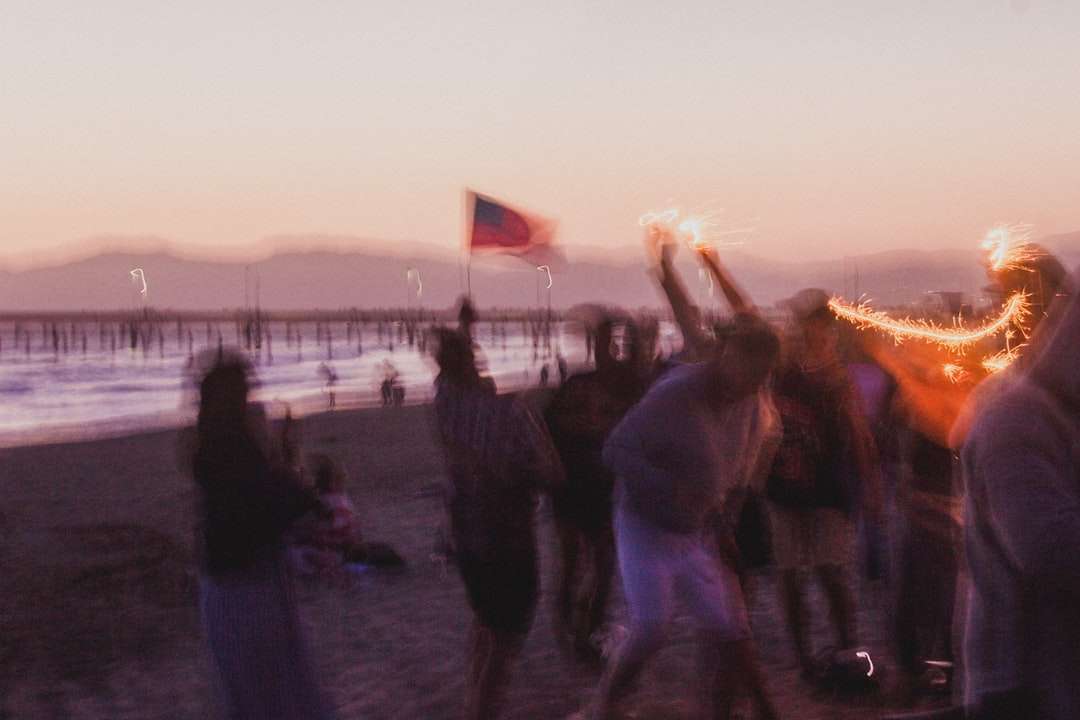 ludzie stojący na brzegu plaży podczas zachodu słońca puzzle online