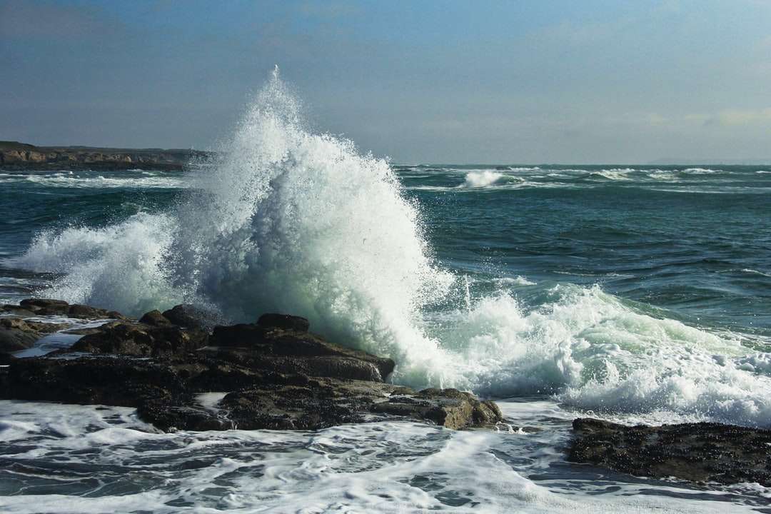 fale oceanu rozbijające się o brunatną formację skalną w ciągu dnia puzzle online