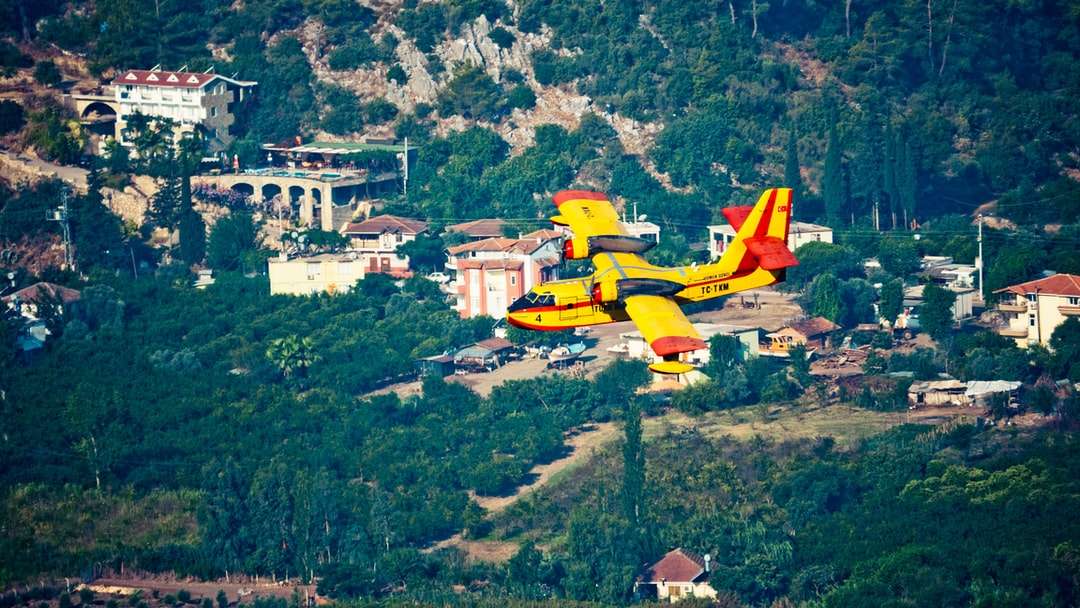 żółty i czerwony samolot lecący nad polem zielonej trawie puzzle online