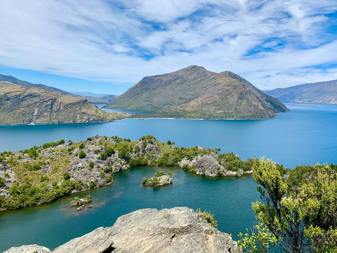 zielona i brązowa góra nad jeziorem pod błękitnym niebem puzzle online